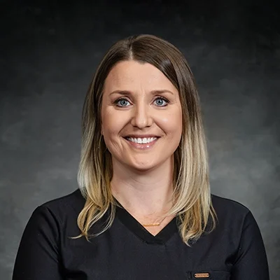 Angie Coffin Smiling In Front Of Grey Background