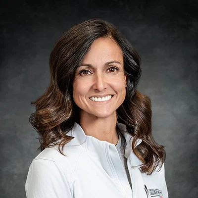 Mina Whitmer Smiling In Front Of Grey Background
