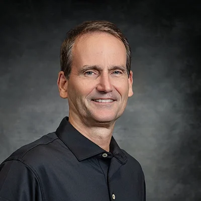 Mark Shuttleworth Smiling In Front Of Grey Background