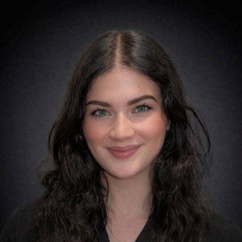 Kimberly Payne Smiling In Front Of Grey Background